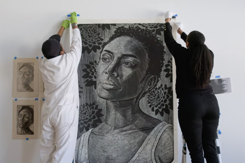LaToya Hobbs installing a large-scale woodblock print portrait